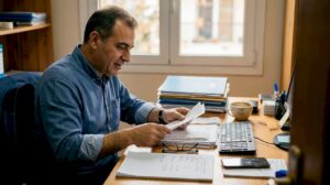 Ιδιοκτήτης επιχείρησης τακτοποιεί τα χαρτιά του στο γραφείο, οργανώνοντας τα έγγραφα και βάζοντας τάξη στις υποχρεώσεις της ημέρας.